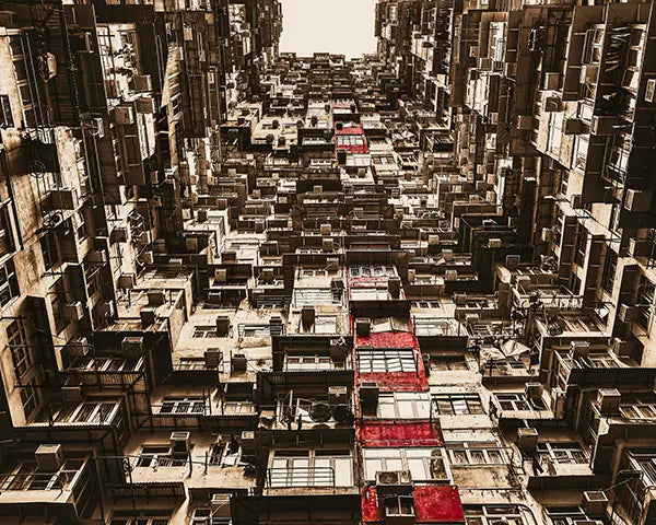 Here you go:

"Dense layers of weathered Hong Kong apartment buildings seen from street level, red accents punctuating the urban maze. Image by Andrew Para Photographic Artslider_item_aF6zJF
