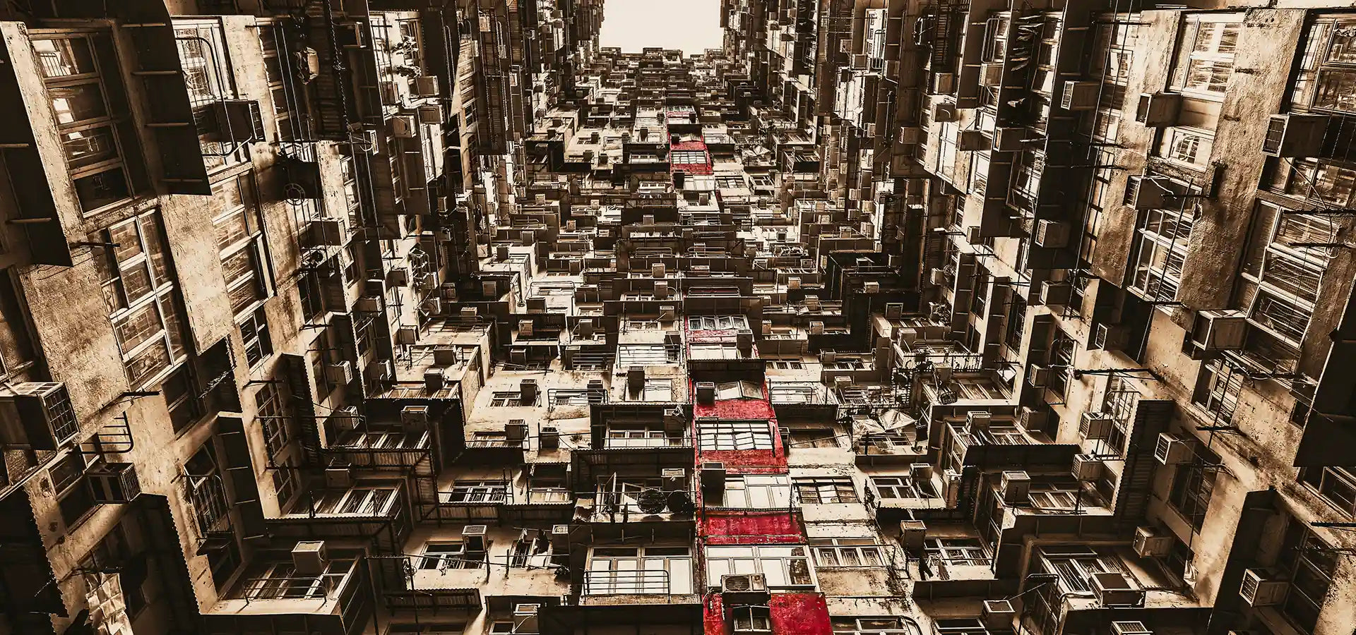 Here you go:

"Dense layers of weathered Hong Kong apartment buildings seen from street level, red accents punctuating the urban maze. Image by Andrew Para Photographic Artslider_item_aF6zJF
